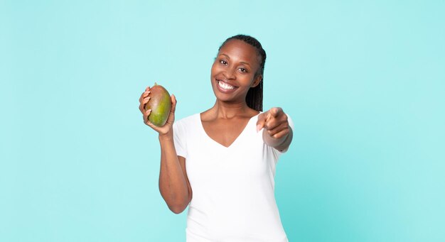 Mujer adulta afroamericana negra sosteniendo una fruta de mango