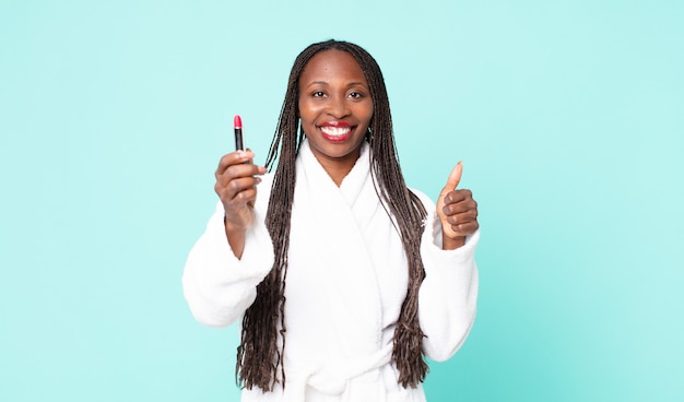 Mujer adulta afroamericana negra vistiendo albornoz y sosteniendo un lápiz labial