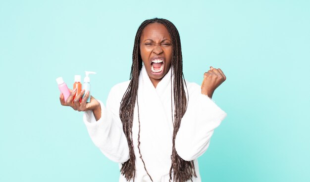 Mujer adulta afroamericana negra vistiendo bata de baño y sosteniendo productos cosméticos