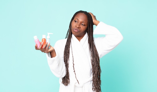 Mujer adulta afroamericana negra vistiendo bata de baño y sosteniendo productos cosméticos