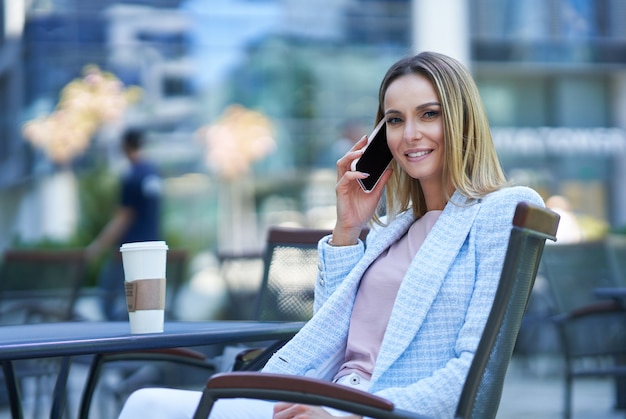 Mujer adulta atractiva con smartphone y relajarse en la ciudad