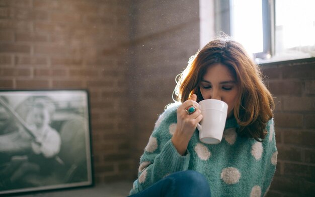 Una mujer adulta bebiendo café en casa.