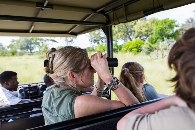 Mujer adulta con binoculares en vehículo safari Botswana