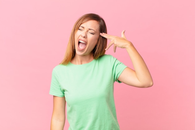 Mujer adulta bonita que parece infeliz y estresada, gesto de suicidio haciendo signo de pistola