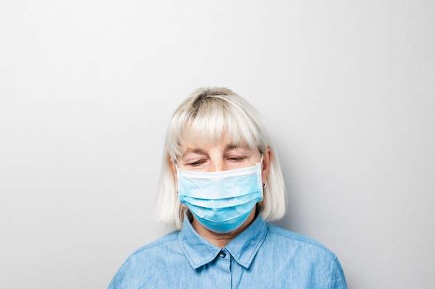 La mujer adulta con cabello rubio usa una máscara médica debido a un brote de virus o contaminación del aire