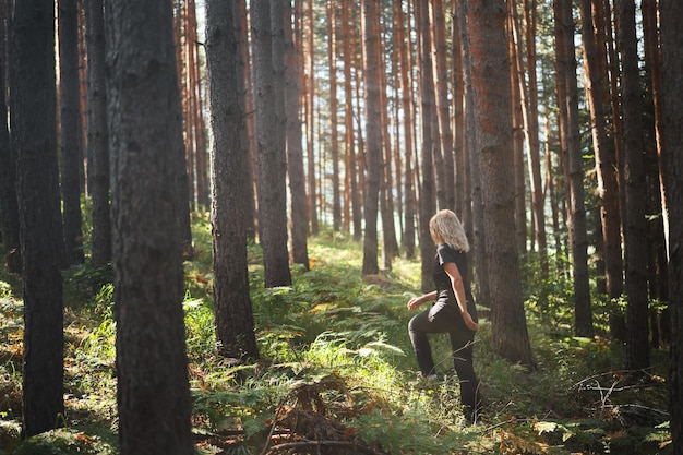 Una mujer adulta camina por un bosque de pinos bajo los rayos del sol de la mañana idea de relajación para bañarse en el bosque