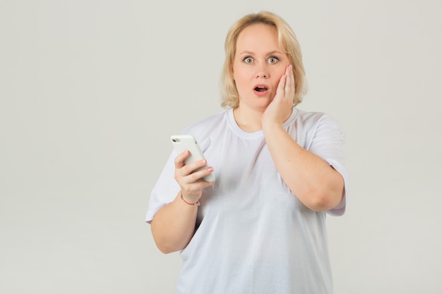 Mujer adulta en una camiseta blanca con un teléfono