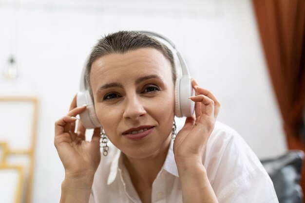 Mujer adulta caucásica con corte de pelo corto escucha música con auriculares