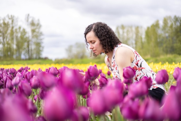 Mujer adulta caucásica mirando flores de tulipán frescas en un campo