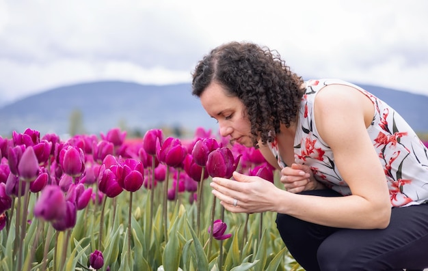 Mujer adulta caucásica mirando flores de tulipán frescas en un campo