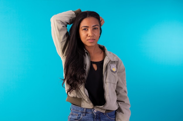 Mujer adulta con chaqueta casual haciendo expresiones faciales en foto de estudio con fondo azul.