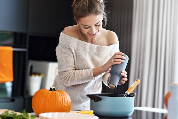 Mujer adulta en la cocina preparando platos de calabaza para Halloween