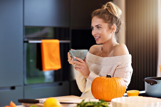 Mujer adulta en la cocina preparando platos de calabaza para Halloween