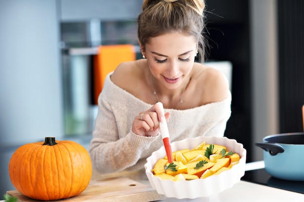 Mujer adulta en la cocina preparando platos de calabaza para Halloween