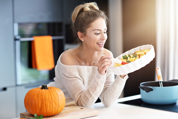 Mujer adulta en la cocina preparando platos de calabaza para Halloween