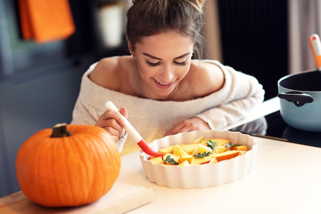 Mujer adulta en la cocina preparando platos de calabaza para Halloween