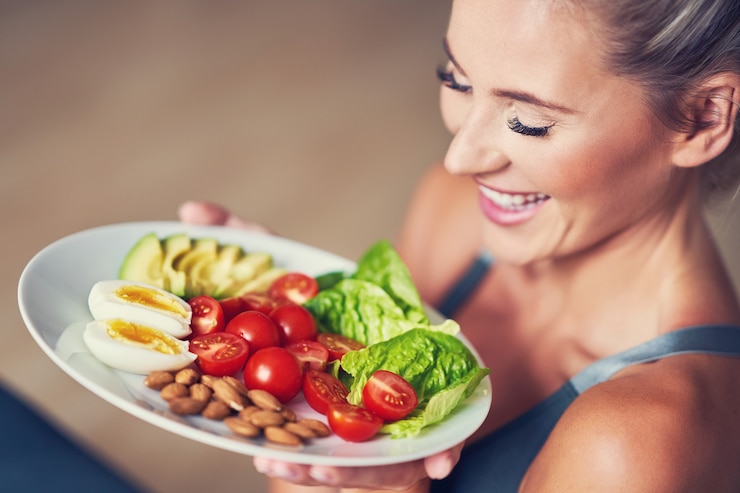 Foto mujer adulta comiendo un almuerzo saludable y sentado en una estera de yoga