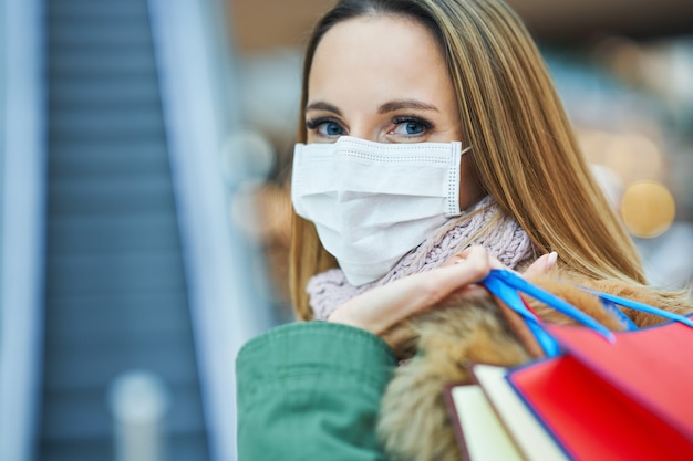 Foto mujer adulta de compras en el centro comercial con una máscara, concepto de coronavirus