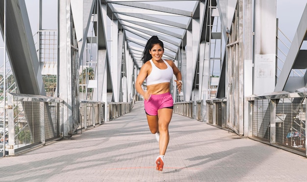 Mujer adulta corriendo en el puente de la ciudad marítima.