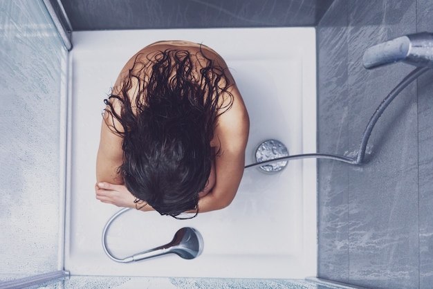 Mujer adulta bajo la ducha en el baño.