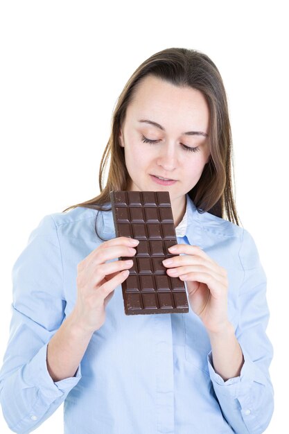 Mujer adulta joven comiendo barra de chocolate sobre fondo blanco aislado