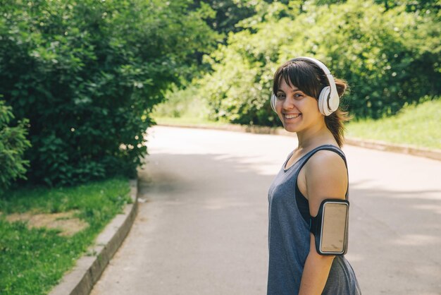 Mujer adulta joven corriendo por el parque de la ciudad con música vidas saludables