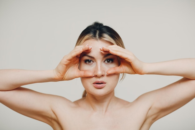 Mujer adulta joven haciendo gimnasia facial auto masaje y ejercicios rejuvenecedores construcción de cara para la piel y los músculos de elevación