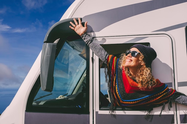 Mujer adulta joven muy contenta que estira los brazos fuera de las ventanas de una autocaravana y celebra la libertad y el estilo de vida de vacaciones de viaje de vacaciones de verano