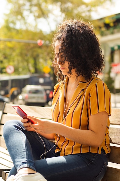 Mujer adulta joven que usa su teléfono inteligente en la calle