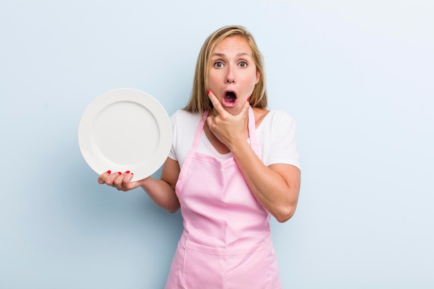 Mujer adulta joven rubia sosteniendo un concepto de chef de plato vacío