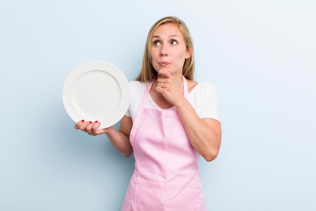 Mujer adulta joven rubia sosteniendo un concepto de chef de plato vacío