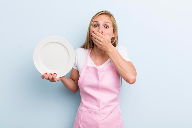 Mujer adulta joven rubia sosteniendo un concepto de chef de plato vacío