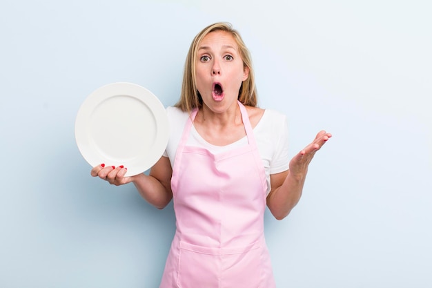 Mujer adulta joven rubia sosteniendo un concepto de chef de plato vacío