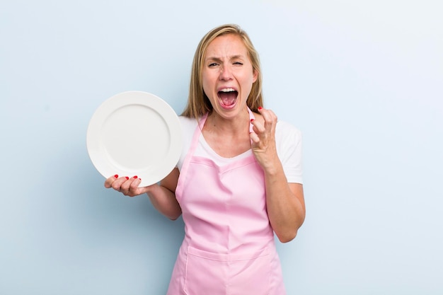 Mujer adulta joven rubia sosteniendo un concepto de chef de plato vacío