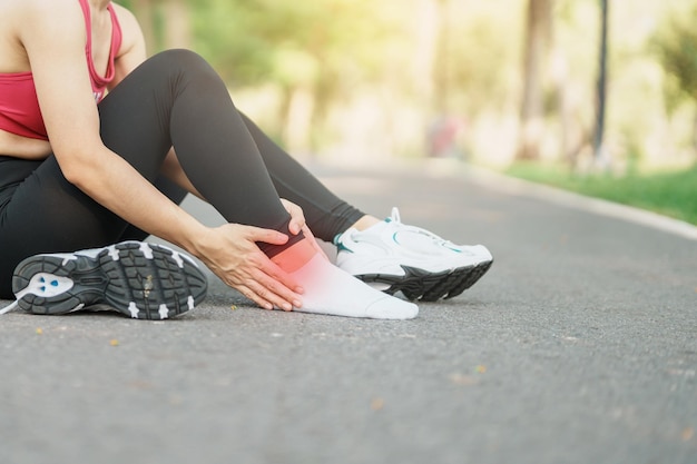 Mujer adulta joven con su dolor muscular durante la carrera mujer corredora con dolor en la pierna debido a esguinces de tobillo o tendinitis de Aquiles Lesiones deportivas y concepto médico