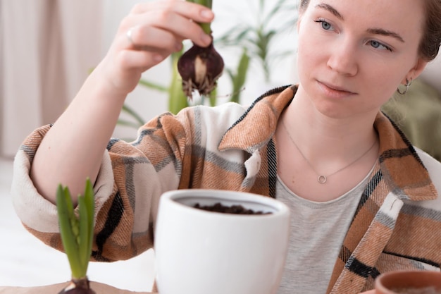 Mujer adulta joven trasplantando plantas a macetas nuevas en casa sentada en el suelo