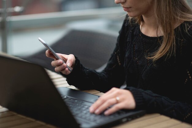 Mujer adulta joven usando computadora portátil y teléfonos inteligentes navegando por la red