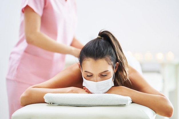 Mujer adulta en máscara durante el masaje relajante en el spa