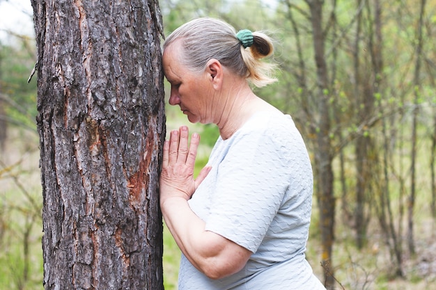 Una mujer adulta medita usando un árbol.