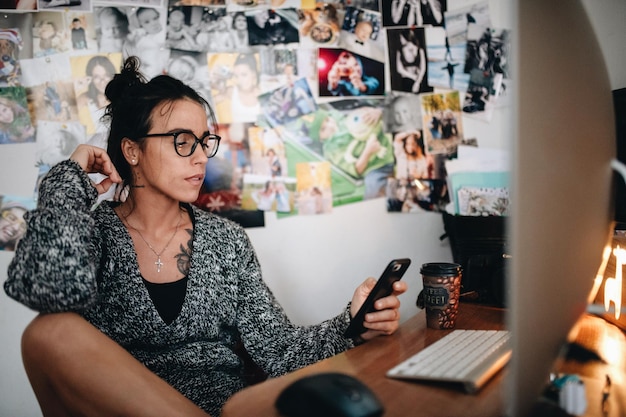 Mujer adulta de mitad de edad usando teléfono móvil mientras está sentada en la mesa
