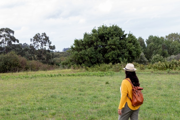 Mujer adulta con una mochila de cuero camina por el camino