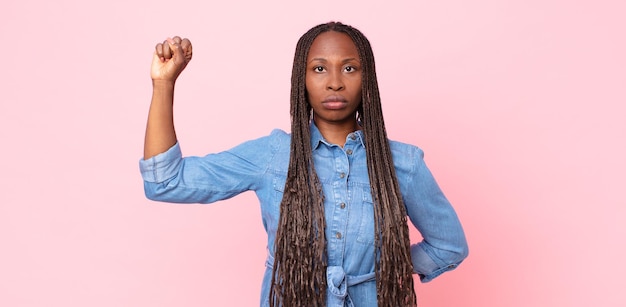 Mujer adulta negra afro que se siente seria, fuerte y rebelde, levantando el puño, protestando o luchando por la revolución