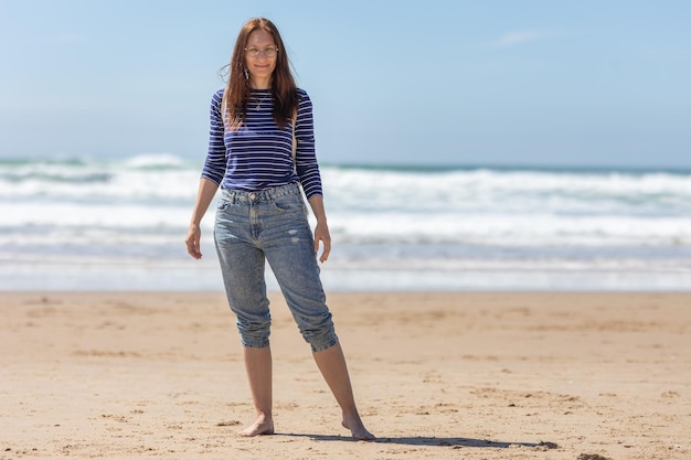 Una mujer adulta parada en la playa del mar