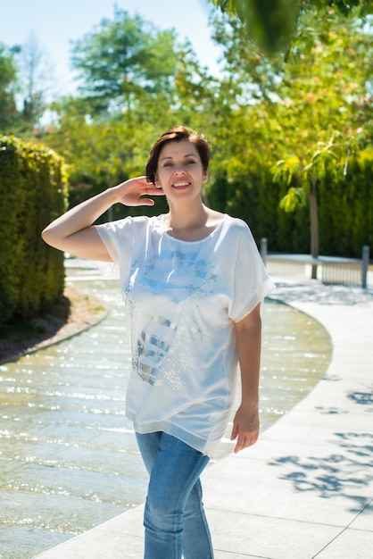 Una mujer adulta en el parque y sonríe.