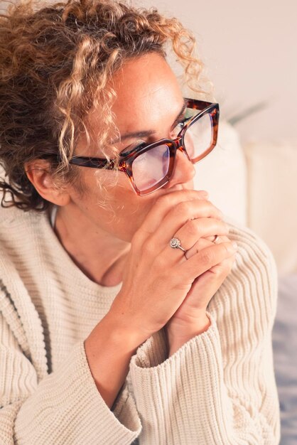 Foto mujer adulta preocupada sentada en el sofá en casa con las manos apretadas y pensando en problemas pensamientos tristes mujeres adultas con expresión de preocupación rompen el concepto de relación economía problema cantidad bancaria vida