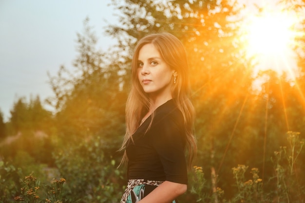 Mujer adulta de retrato al aire libre en la naturaleza caminando en el bosque de verano del atardecer. Señora soñadora en desgaste caminar por la noche en un parque. Emoción positiva de la mujer en el parque al amanecer