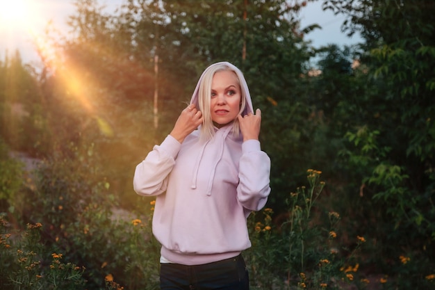 Mujer adulta de retrato al aire libre en la naturaleza caminando en el bosque de verano del atardecer. Señora soñadora en desgaste caminar por la noche en un parque. Emoción positiva de la mujer en el parque al amanecer