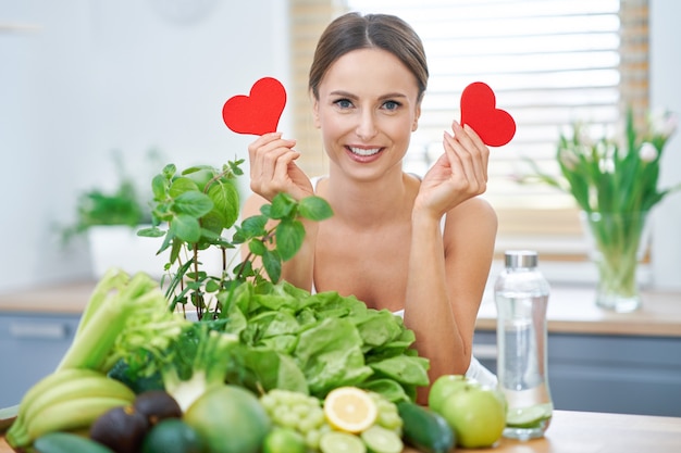 Mujer adulta sana con comida verde en la cocina