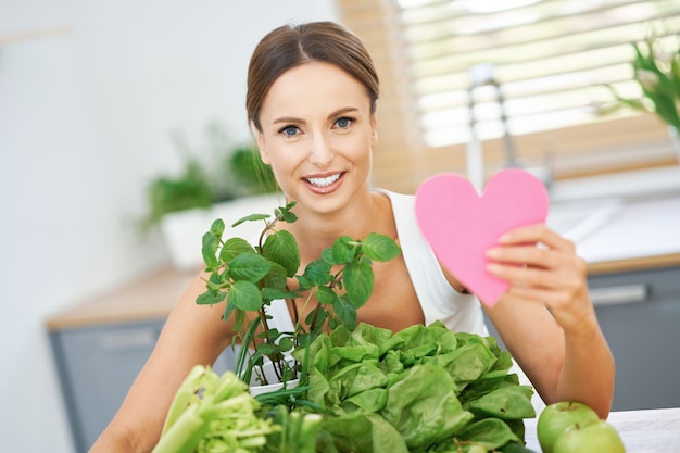 Mujer adulta sana con comida verde en la cocina