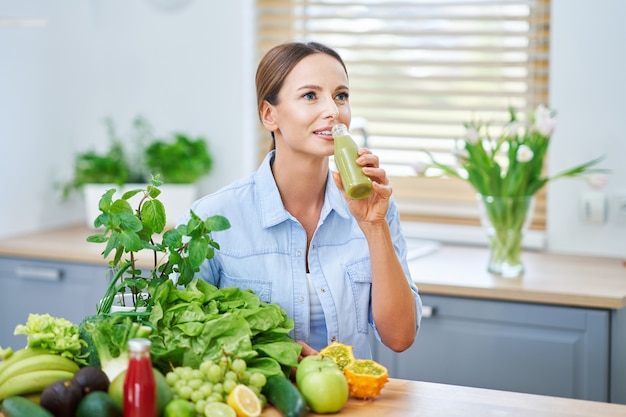 Mujer adulta sana con comida verde en la cocina